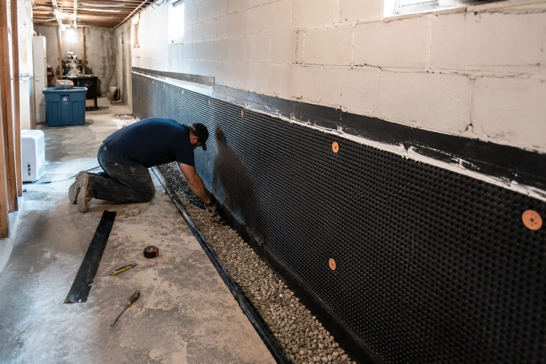 Interior basement waterproofing installation with drainage matting and gravel channel